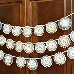 May include: A white banner with gray scalloped circles that spell out "Happy 60th Anniversary Paul & 60".