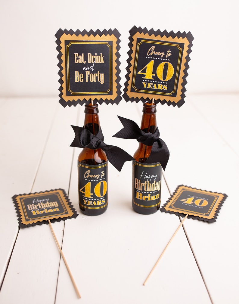May include: Four black and gold party decorations with the text "Eat, Drink and Be Forty", "Cheers to 40 Years", "Happy Birthday Brian" and "40".