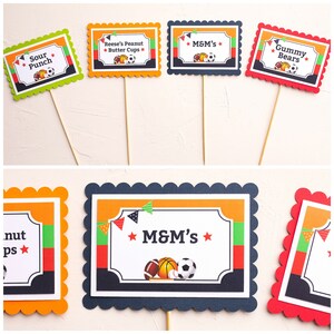 May include: Set of ten printable food labels for a sports-themed party. The labels feature a variety of sports equipment, including a baseball bat, baseball, basketball, football, and soccer ball. The labels are in orange, red, green, and blue with white text. The text on the labels includes "Sour Punch", "Reese's Peanut Butter Cups", "M&M's", "Gummy Bears", and "M&M's".