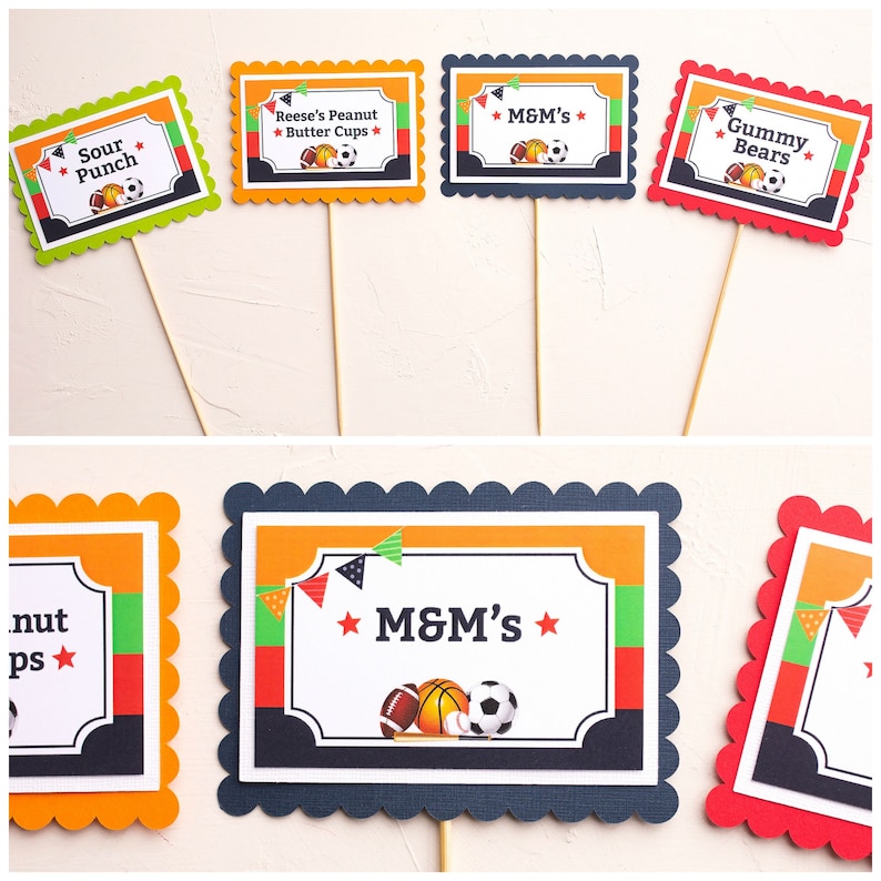 May include: Set of ten printable food labels for a sports-themed party. The labels feature a variety of sports equipment, including a baseball bat, baseball, basketball, football, and soccer ball. The labels are in orange, red, green, and blue with white text. The text on the labels includes "Sour Punch", "Reese's Peanut Butter Cups", "M&M's", "Gummy Bears", and "M&M's".