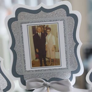 May include: A silver glitter picture frame with a black and white photo of a couple. The frame has a scalloped edge and a silver ribbon tied around it.