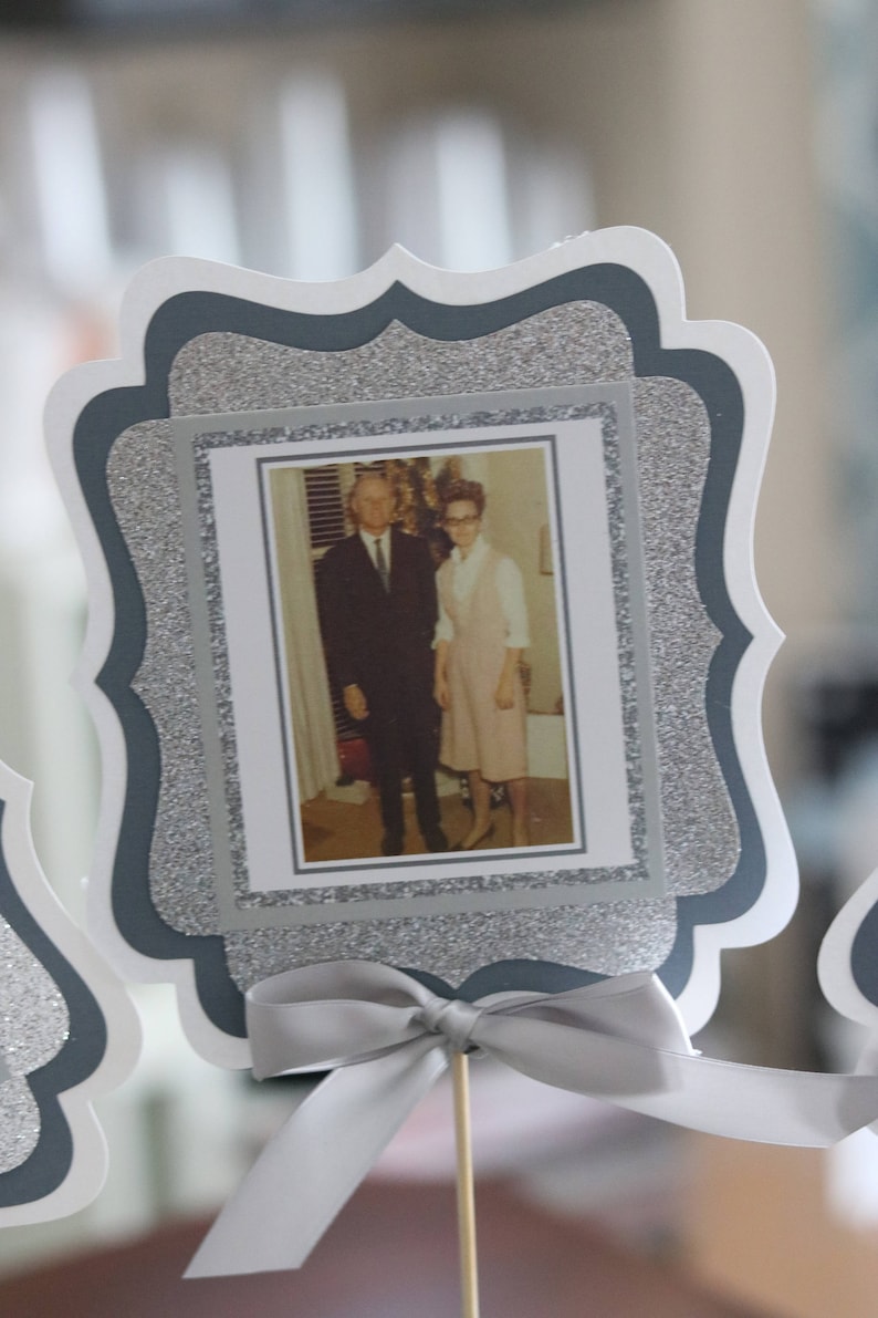 May include: A silver glitter picture frame with a black and white photo of a couple. The frame has a scalloped edge and a silver ribbon tied around it.
