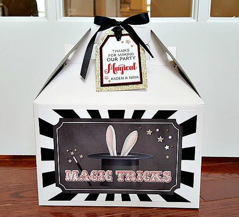 Pu&ograve; includere: Scatola regalo bianca con strisce bianche e nere. La scatola ha un'illustrazione in bianco e nero di un cappello da mago con orecchie di coniglio e il testo "Magic Tricks". Un'etichetta &egrave; attaccata alla scatola con il testo "Grazie per aver reso la nostra festa magica Kaden & Naya".