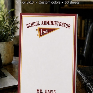 May include: A personalized notepad with a white background and a maroon border. The text reads SCHOOL ADMINISTRATOR at the top, a maroon and gold pennant graphic with the word Lead, and MR. DAVIS at the bottom. It is 5x7 or 8x10 inches.