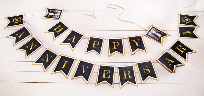 Puede incluir: Una pancarta negra y dorada con las palabras "Happy Anniversary" en letras doradas. La pancarta tiene un marco de fotos en cada extremo con una foto de una pareja.