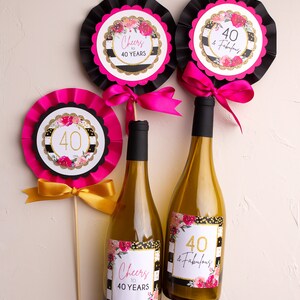 May include: Three wine bottles decorated with black and white striped labels with gold glitter and pink flowers. The labels say "Cheers to 40 Years" and "40 & Fabulous".