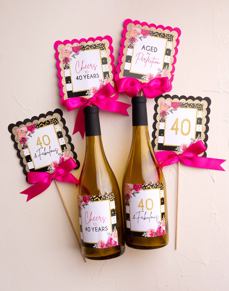 May include: Two wine bottles with black and white striped labels featuring gold glitter and floral accents. The labels read "Cheers to 40 Years" and "40 & Fabulous".  There are four decorative signs with black and white stripes, gold glitter, and floral accents. The signs read "Cheers to 40 Years", "Aged to Perfection", "40 & Fabulous", and "40".