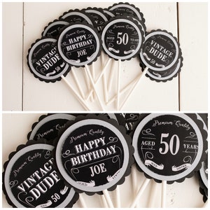 May include: Black and white cupcake toppers with scalloped edges. The toppers feature the text "Vintage Dude", "Happy Birthday Joe", and "Aged 50 Years".