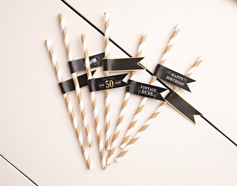 May include: Set of six gold and white striped paper straws with black flags. The flags have the text "Happy Birthday", "Vintage Dude", and "Aged 50 Years".