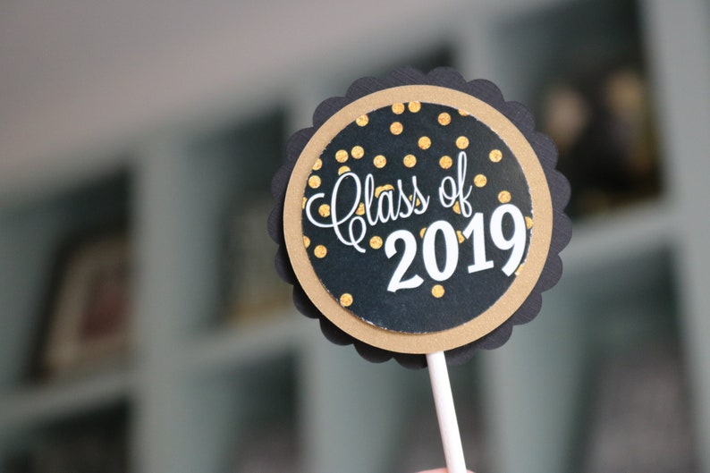 May include: Black and gold round cake topper with the text "Class of 2019" on a white stick.