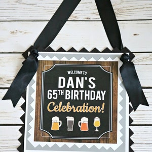May include: Welcome to Dan's 65th Birthday Celebration! A black and white sign with a wood grain background and a chalkboard center. The sign has a scalloped border and is decorated with four beer mugs.
