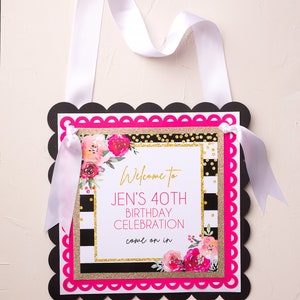 以下が含まれることがあります： 黒と白のストライプの背景に、金色のグリッターとピンクの花のアクセントが施されています。テキストには「Jenの40歳の誕生日のお祝いにようこそ、どうぞお入りください」と書いてあります。