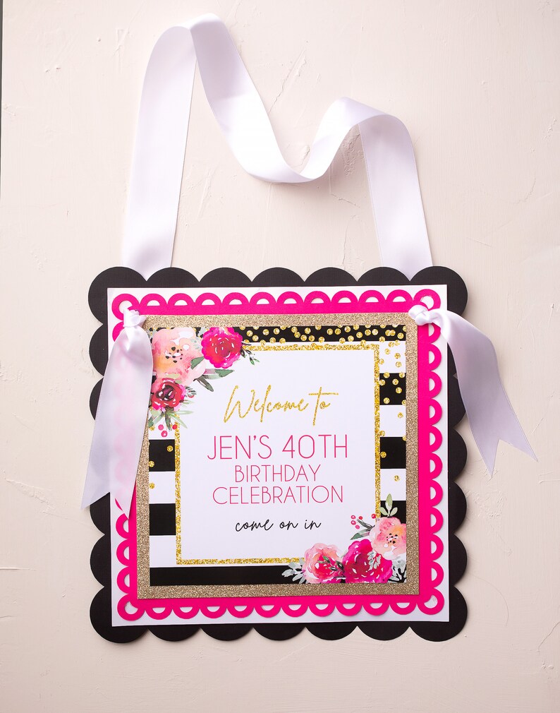 以下が含まれることがあります： 黒と白のストライプの背景に、金色のグリッターとピンクの花のアクセントが施されています。テキストには「Jenの40歳の誕生日のお祝いにようこそ、どうぞお入りください」と書いてあります。