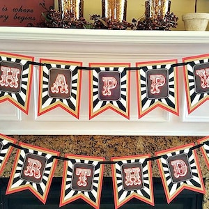 Op de afbeelding: Een zwart-wit gestreepte banner met rode accenten luidt "Happy Birthday". Elke letter staat in een rood kader met een witte achtergrond. De banner is versierd met zwarte hoge hoeden met witte konijnenoren.