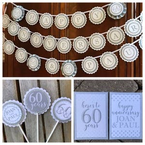 May include: A set of 60th anniversary party decorations in silver and white. The set includes a banner that says "Happy Anniversary", three cake toppers with the number 60 and the words "60 years", and two signs that say "Here's to 60 years" and "Happy Anniversary Joan & Paul".