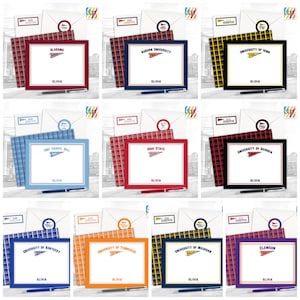 May include: A selection of personalised stationery sets, each displaying a university logo. Each set includes a notepad, envelopes, and a pen. The notepads feature a framed design with the university name and a pennant logo. The sets are in various colours, including red, blue, and yellow.