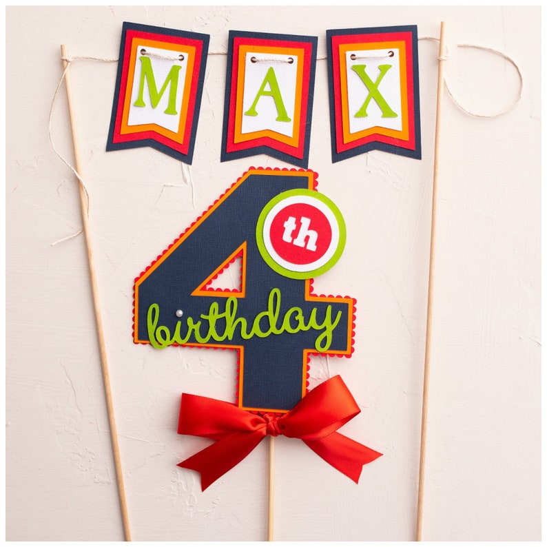 May include: A blue and red cake topper with the number 4 and the words "birthday" and "th" in green. The topper is decorated with a red bow and is attached to a wooden stick.