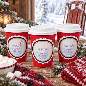 May include: Three red paper cups with white lids, each featuring a circular label with a light blue mug illustration, marshmallows, a red and white striped straw, and the text Hot Cocoa in red script, arranged on a rustic wooden surface.