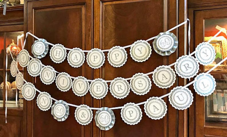 May include: A white banner with gray scalloped circles that spell out "Happy 60th Anniversary Paul & 60".