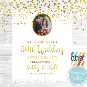 May include: A white poster with gold confetti and a photo of a couple in the center. The text reads "Welcome to the 50th Wedding Anniversary Celebration of Kathy & Bill 50 Years of Love".