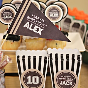 K&ouml;nnte beinhalten: Zwei schwarz-wei&szlig; gestreifte Popcorn-Boxen mit braunen Papierkreisen. Eine Box hat die Nummer "10" in Wei&szlig; auf dem Kreis. Die andere Box hat den Text "Happy Birthday Jack" auf dem Kreis.