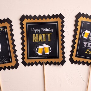 May include: Three black and gold party decorations with a scalloped edge. The centre decoration says "Happy Birthday MATT" with two beer mugs. The left decoration says "50" and the right decoration says "50 YEARS LOVED".