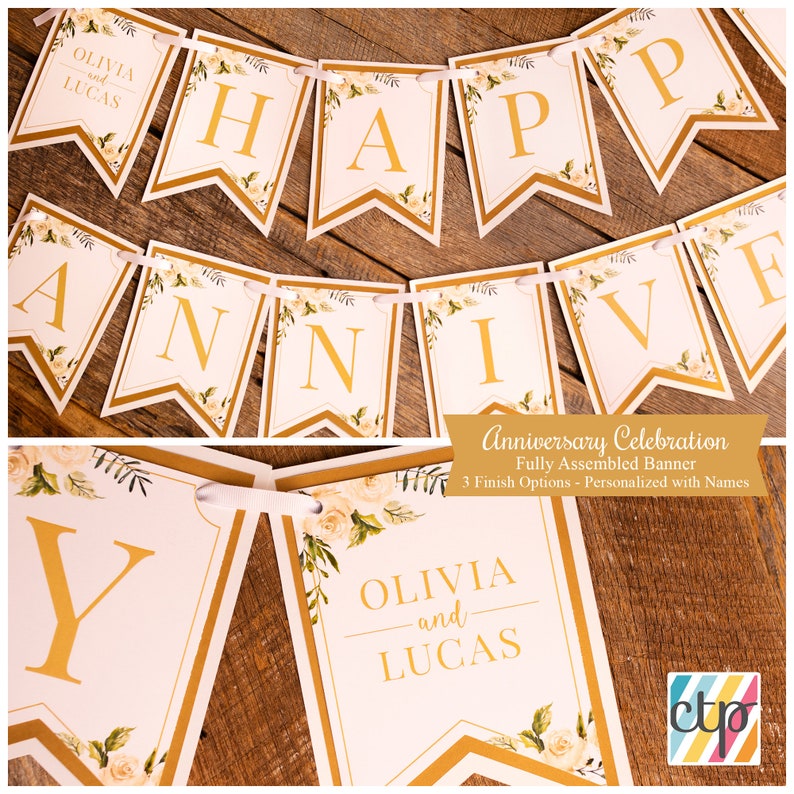 K&ouml;nnte beinhalten: Ein wei&szlig;-goldenes Banner mit den Worten "Happy Anniversary" und den Namen "Olivia und Lucas". Das Banner ist mit wei&szlig;en Rosen und gr&uuml;nen Bl&auml;ttern verziert.