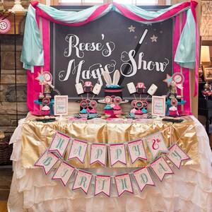 May include: A birthday party table setting with a pink and blue color scheme. The table is decorated with a banner that says "Happy 8th Birthday". There is a sign that says "Reese's Magic Show" and cupcakes with a magic theme.