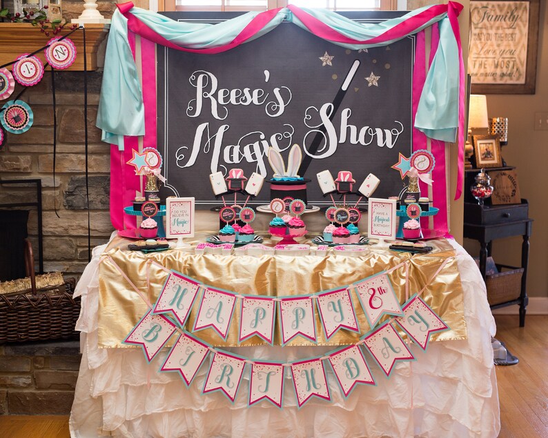 May include: A birthday party table setting with a pink and blue color scheme. The table is decorated with a banner that says "Happy 8th Birthday". There is a sign that says "Reese's Magic Show" and cupcakes with a magic theme.
