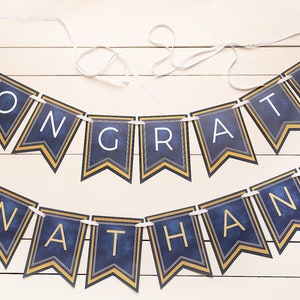 May include: A navy blue and gold graduation banner with the words "Congrats Nathan" and the year "2023" on each end.