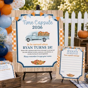 May include: A Time Capsule sign for a 1st birthday party featuring a light blue truck carrying pumpkins, orange and blue bunting, and text reading Time Capsule 2036 to be opened when RYAN TURNS 18, alongside matching message cards in a wooden box.