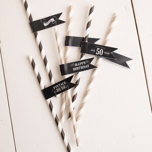Puede incluir: Pajitas de papel rayadas en blanco y negro con banderas negras. Las banderas tienen el texto "Vintage Dude", "Happy Birthday" y "Aged 50 Years".