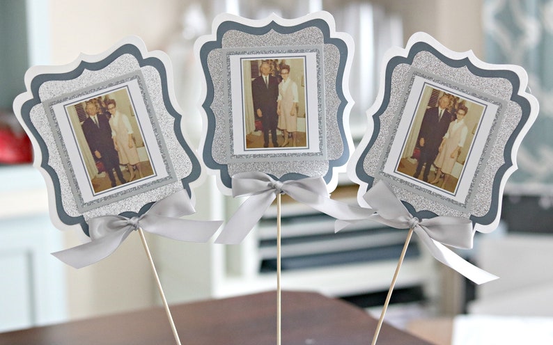 May include: Three silver glitter picture frames with white borders and a silver ribbon bow. Each frame holds a black and white photo of a couple.