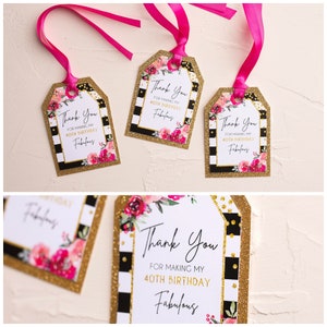 以下が含まれることがあります： 金色のグリッターのアクセントとピンクの花柄のデザインが施された、黒と白のストライプのギフトタグ4枚。タグには「私の40歳の誕生日を素晴らしいものにしてくれてありがとう」というテキストが書かれています。