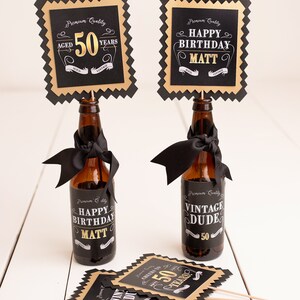 May include: Two black and gold party decorations with the text "Aged 50 Years" and "Happy Birthday Matt". Two brown glass bottles with black and gold labels that say "Happy Birthday Matt" and "Vintage Dude 50".