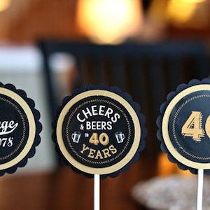 May include: Three black and gold round cupcake toppers with scalloped edges. The toppers feature the text "Vintage 1978", "Cheers & Beers to 40 Years", and "40".