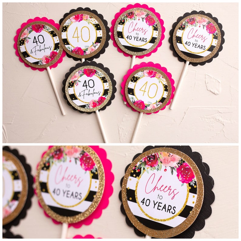 May include: A collection of decorative cupcake toppers for a 40th birthday celebration. The toppers feature a black and white striped background with gold glitter accents, floral designs, and the phrases "40 & Fabulous" and "Cheers to 40 Years."
