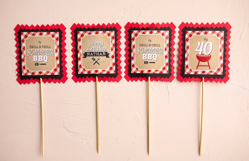 Puede incluir: Cuatro adornos para fiestas con bordes a cuadros rojos y negros. Los adornos tienen texto que dice "GRILL & CHILL SUMMER BBQ", "Happy Birthday NATHAN" y "40" con un gr&aacute;fico de barbacoa. Los adornos est&aacute;n sobre palitos de madera.