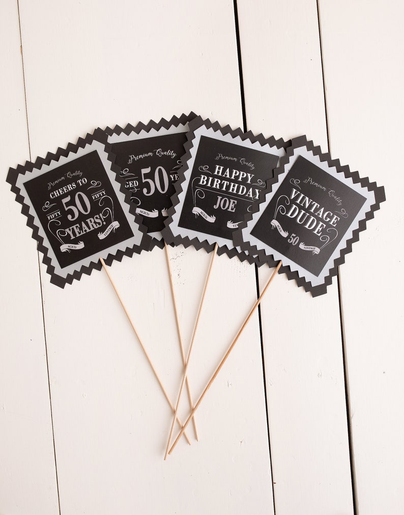 Puede incluir: Cuatro accesorios de cabina de fotos en blanco y negro con un tema de cumplea&ntilde;os n&uacute;mero 50. Los accesorios presentan el texto "Cheers to 50 Years!" "50", "Happy Birthday Joe" y "Vintage Dude".