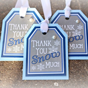 May include: Three blue and gray gift tags with white ribbon. The tags have a scalloped edge and say "Thank You Snow Much".