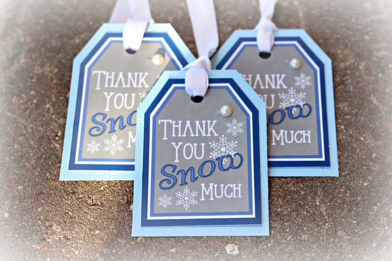 May include: Three blue and gray gift tags with white ribbon. The tags have a scalloped edge and say "Thank You Snow Much".