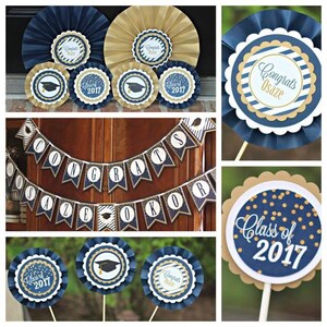 May include: Graduation party decorations in navy blue and gold. The decorations include a banner that says "Congrats Osaz&eacute; Okor", paper fans with gold and navy blue stripes, and a paper fan with gold confetti and the text "Class of 2017".
