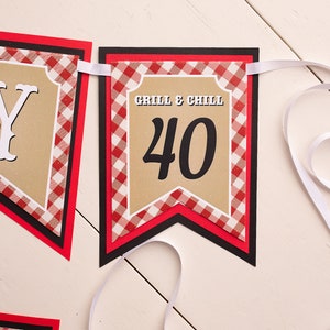 Peut inclure: Une guirlande avec les mots "Grill & Chill" et le chiffre "40" sur un fond beige. La guirlande a une bordure &agrave; carreaux rouges et blancs et est attach&eacute;e avec un ruban blanc. La guirlande est con&ccedil;ue pour une c&eacute;l&eacute;bration du 40e anniversaire.