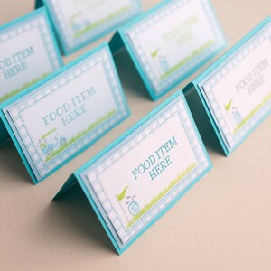 May include: Five blue and white food labels with a golf cart design and the text "Food Item Here".
