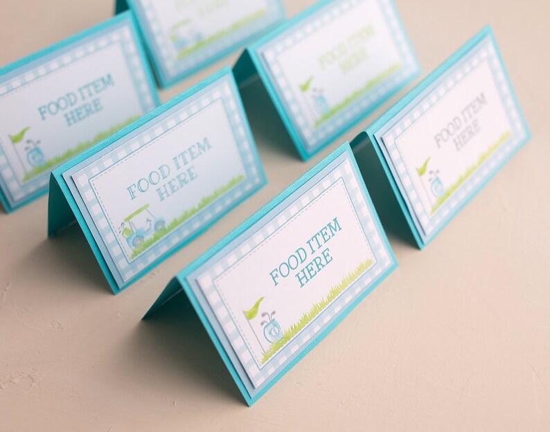 May include: Five blue and white food labels with a golf cart design and the text "Food Item Here".