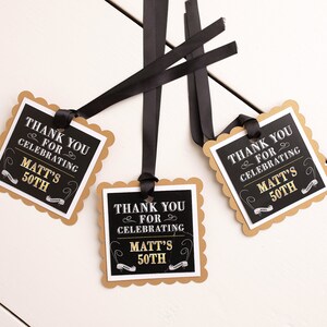 May include: Three black and gold favor tags with scalloped edges. The tags are tied with black ribbon and feature the text "Thank you for celebrating Matt's 50th".