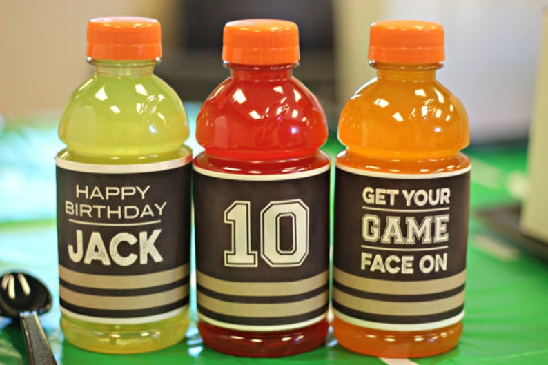 K&ouml;nnte beinhalten: Drei durchsichtige Plastikflaschen mit orangenen Deckeln und schwarz-wei&szlig;en Etiketten. Die Etiketten haben unterschiedliche Texte, darunter "Happy Birthday Jack", "10" und "Get Your Game Face On".