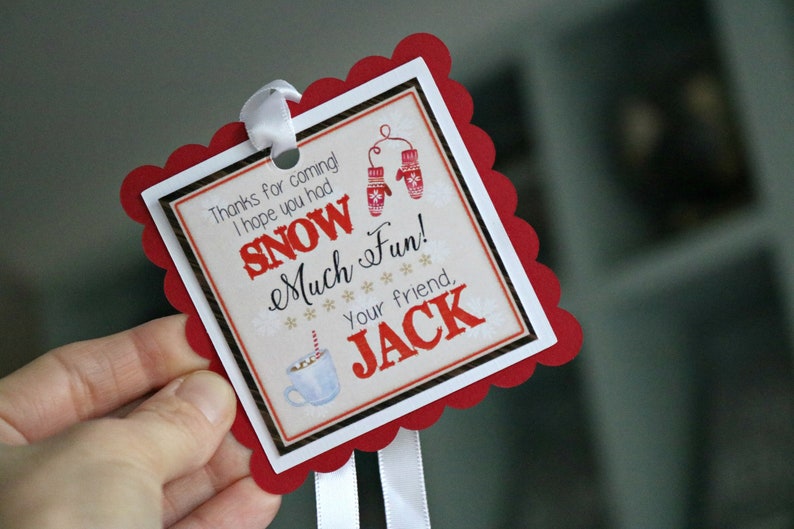 May include: A square gift tag with a red scalloped border and white ribbon. The center features the text 'Thanks for coming! I hope you had SNOW Much Fun! Your friend, JACK' alongside illustrations of red mittens and a blue mug with a striped straw.