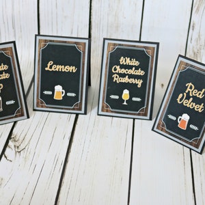 May include: Four black chalkboard signs with white text and images of beer mugs. The signs read "Chocolate Chocolate Chip", "Lemon", "White Chocolate Raspberry", and "Red Velvet".