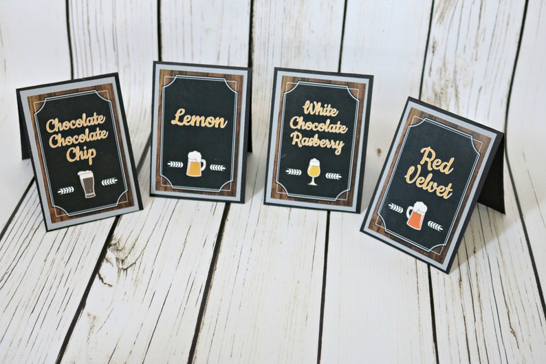 May include: Four black chalkboard signs with white text and images of beer mugs. The signs read "Chocolate Chocolate Chip", "Lemon", "White Chocolate Raspberry", and "Red Velvet".